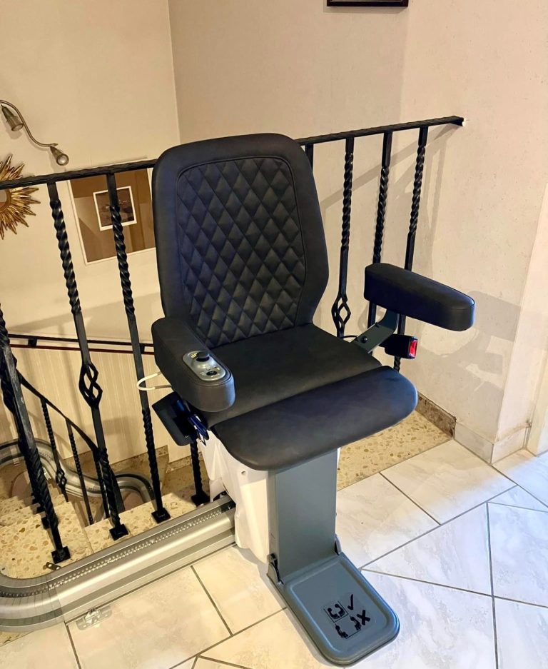 Treppenlift mit gepolsterter Sitzfläche und Armlehnen an einem Geländer montiert. Treppenlift mit gepolsterter Sitzfläche und Armlehnen an einem Geländer montiert.